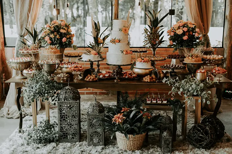 Mesa do bolo decorada com flores e doces no salão