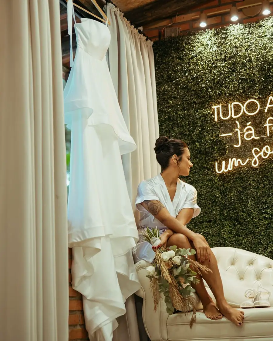 Noiva no camarim ao lado do vestido