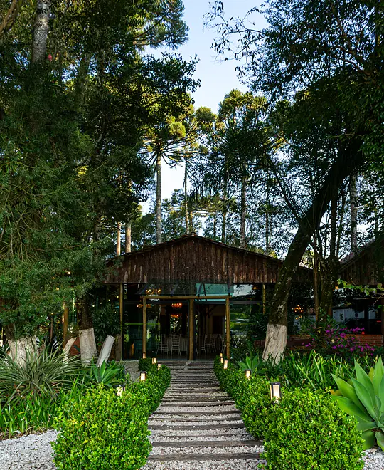 Caminho de pedra entre jardins e luminárias até o salão