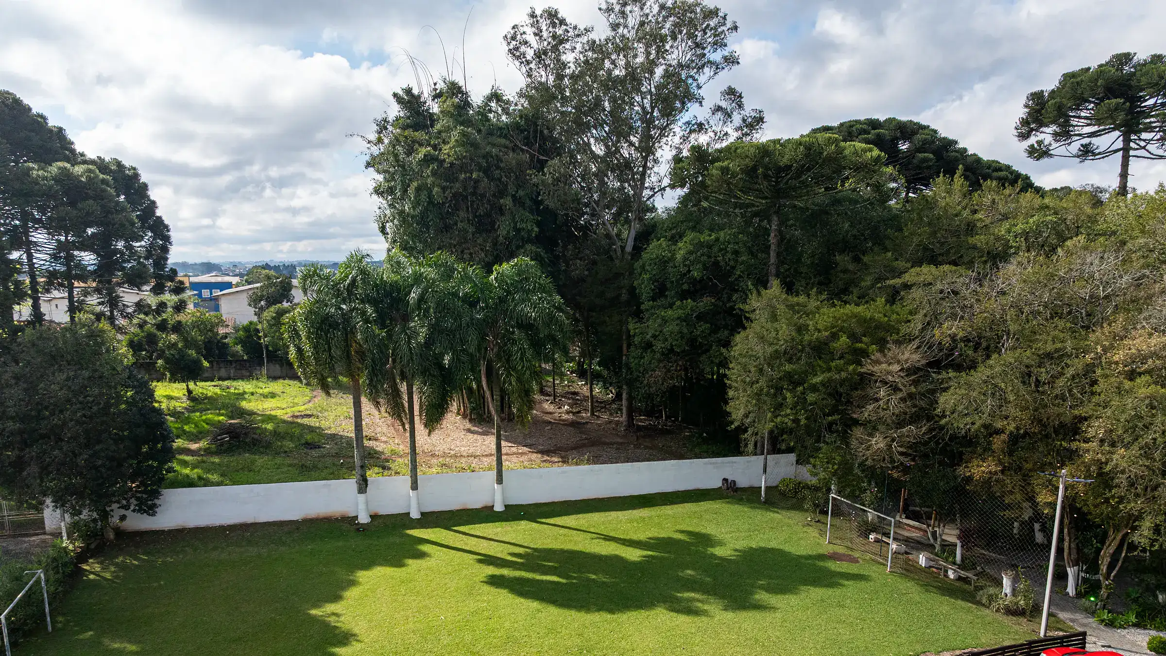 Vista aérea do gramado, do bosque e do estacionamento interno da chácara